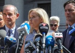 FILE - Virginia Giuffre, center, who says she was trafficked by sex offender Jeffrey Epstein, holds a news conference outside a Manhattan court in New York, Aug. 27, 2019.