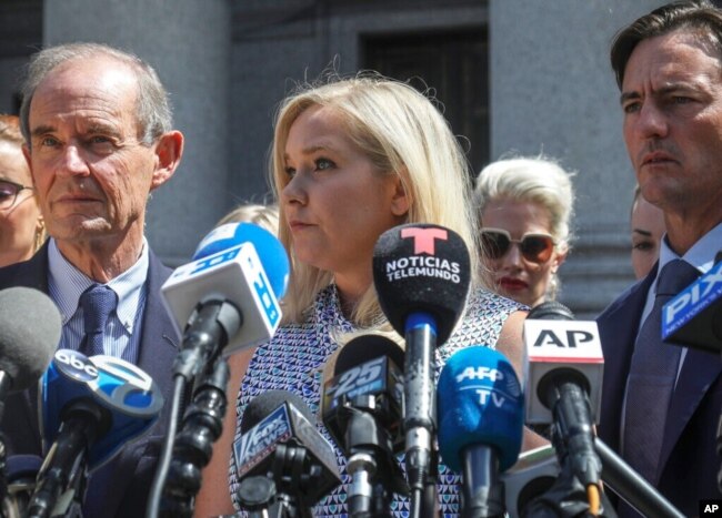 FILE - Virginia Giuffre, center, who says she was trafficked by sex offender Jeffrey Epstein, holds a news conference outside a Manhattan court in New York, Aug. 27, 2019.