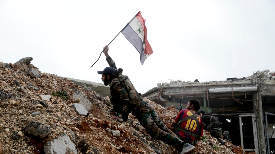 Seorang tentara Suriah menempatkan bendera nasional Suriah saat bertempur dengan pejuang pemberontak timur dari Aleppo, 5 Desember 2016. (AP Photo/Hassan Ammar). 