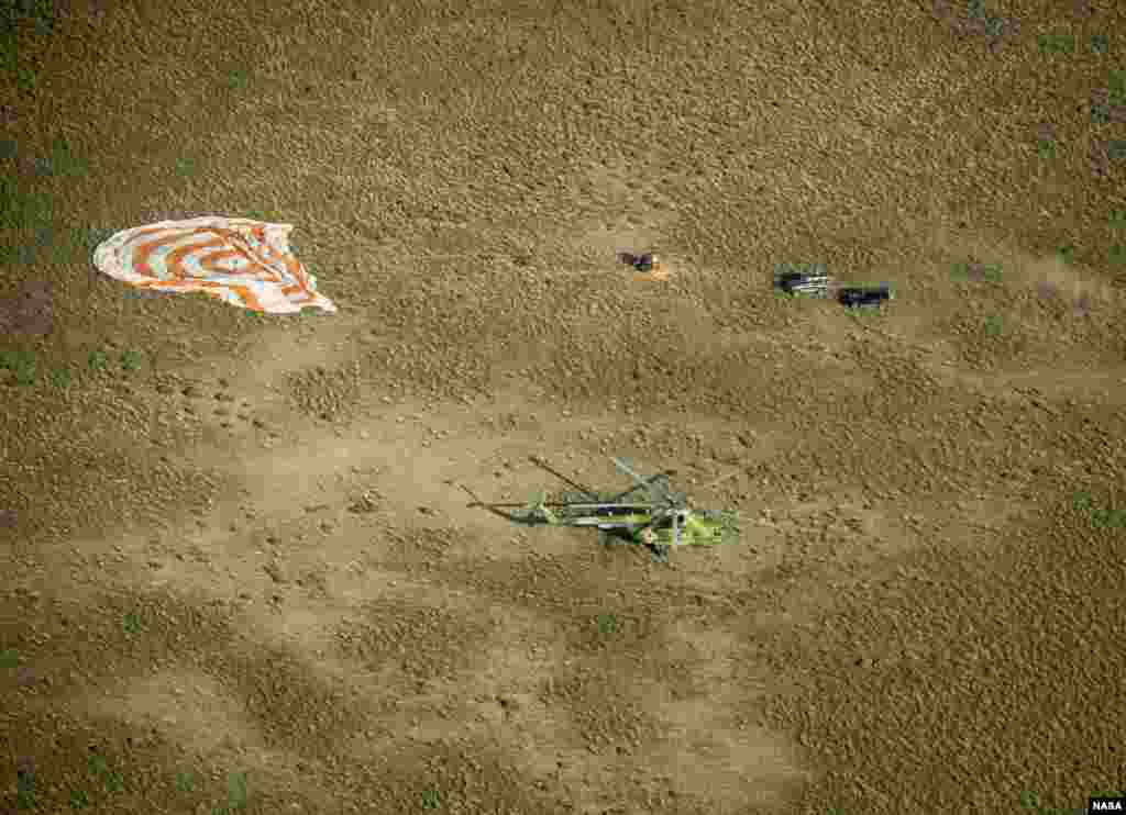 Ground personnel arrive at the landing site seconds after the Soyuz TMA-11M spacecraft landed with Expedition 39 Commander Koichi Wakata of the Japan Aerospace Exploration Agency (JAXA), Soyuz Commander Mikhail Tyurin of Roscosmos, and Flight Engineer Rick Mastracchio of NASA near the town of Zhezkazgan, Kazakhstan.