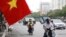 FILE - People wearing face masks to help curb the spread of the coronavirus ride mopeds in Hanoi, Vietnam on Thursday, Aug. 6, 2020. 
