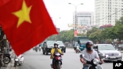 People wearing face masks to help curb the spread of the coronavirus ride mopeds in Hanoi, Vietnam on Aug. 6, 2020.