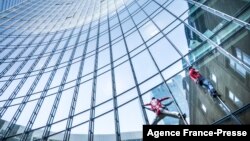 Alain Robert (kiri), yang dikenal sebagai "Spiderman Prancis", dan Leo Urban memanjat gedung Menara SKYPER setinggi 153,8 meter di Frankfurt am Main, Jerman barat pada 23 November 2021. (Foto: AFP )