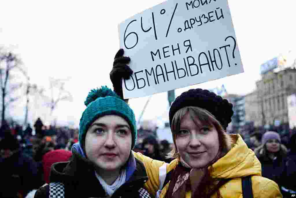 Antonina Shevchenko (left) and Tatyana Pariva, 19-year-old college students, hold a sign that says, "Are 64 percent of my friends lying to me?" Prime Minister Vladimir Putin won Sunday's presidential election with almost 64 percent of the vote, March 5, 2
