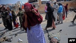 Quelques personnes passent près des corps de trois combattants présumés Shabaab à Mogadiscio, le 14 juillet 2018.