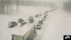 Dalam foto yang diambil dari potongan video lalu lintas Caltrans, tampak kendaraan berjejer di area jalanan di Donner Summit, California, yang dibanjiri salju pada 23 Desember 2021. (Foto: AP)