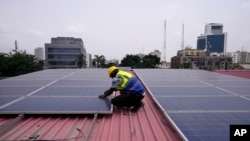 Oladapo Adekunle, an engineer with Rensource Energy, installs solar panels on a roof of a house in Lagos, Nigeria, Thursday, March 21, 2024. (AP Photo/Sunday Alamba)