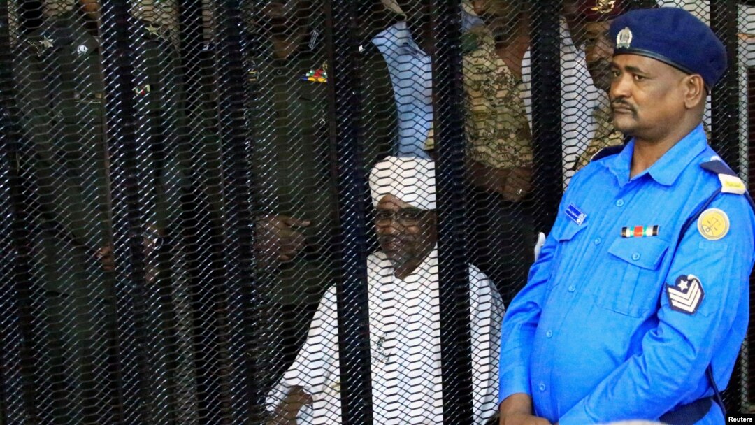 Mantan Presiden Sudan, Omar Hassan al-Bashir duduk di dalam kurungan saat menhadiri sidang atas tuduhan korupsi, di gedung pengadilan Khartoum, Sudan, 19 Agustus 2019.