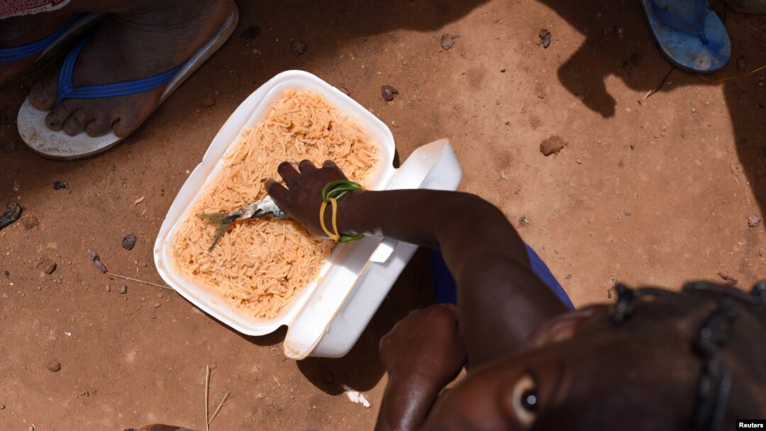FILE - A child, who fled with others from his village in northern Burkina Faso following attacks by assailants, eats inside a school on the outskirts of Ouagadougou, June 15, 2019. 