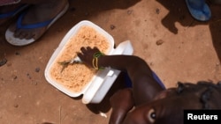 FILE - A child, who fled with others from his village in northern Burkina Faso following attacks by assailants, eats inside a school on the outskirts of Ouagadougou, June 15, 2019. 