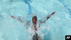 A child cools off in a public pool in Soweto, South Africa, Jan. 17, 2014. 