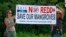 FILE - Two protesters from environmental groups protest holding up a banner against the REDD, the UN program to reduce deforestation and forest degradation in developing countries.