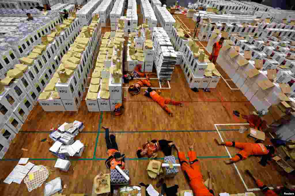 Workers take a break as they prepare election materials in a warehouse in Jakarta, Indonesia.