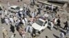 Pakistani police, rescue workers and civilians push back a police vehicle which was hit by roadside bomb, in Peshawar, Pakistan, May 12, 2012.