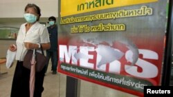 A woman wearing a mask walks past an information banner on Middle East Respiratory Syndrome (MERS) at the entrance of Bamrasnaradura Infectious Diseases Institute on the outskirts of Bangkok, Thailand, June 19, 2015. 