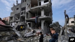 FILE - Palestinians inspect the rubble of a building of the Al Nawasrah family destroyed in an Israeli strike in Maghazi refugee camp, central Gaza Strip, December 25, 2023. 