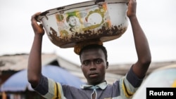 A man balances a bowl with a print of the old Nigerian naira banknote on his head at a local market in Agege district in Lagos, Nigeria, Aug. 16, 2016.