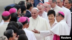 Paus Fransiskus (tengah) mendapat sambutan hangat sambil diapit oleh Presiden Korea Selatan Park Geun-hye (kedua kiri) ketika tiba di Pangkalan Udara Seoul di Seongnam, 14 Agustus 2014.