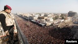 Seorang polisi Irak tengah mengawasi jalannya prosesi pemakaman korban bentrokan antara petugas keamanan dan warga di n Falluja, 50 kilometer sebelah barat Baghdad, 26 January 2013. (REUTERS/Thaier Al-Sudani). Kelompok terkait al-Qaida di Irak menghimbau warga SUni untuk mengangkat senjata melawan pemerintah yang dipimpin golongan Syiah (1/2).