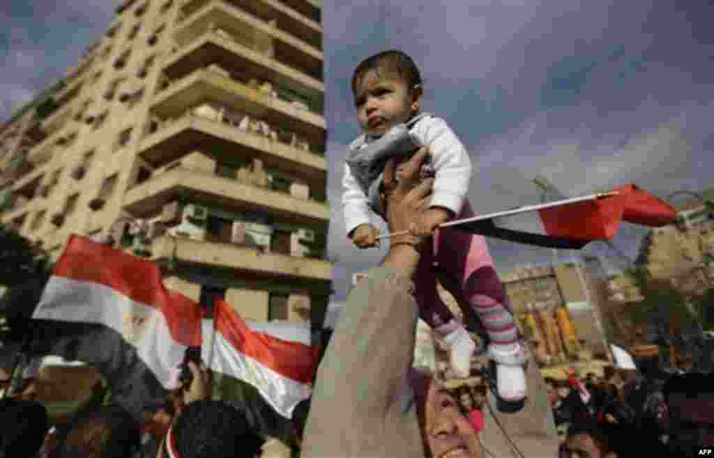 A father holds his child aloft at the continuing anti-government demonstration in Tahrir Square in downtown Cairo, Egypt Thursday, Feb 10, 2011. (AP Photo/Ben Curtis)