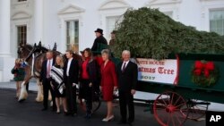 La primera dama de EE.UU., Melania Trump (3a. desde la derecha), su hijo Barron (3o. desde la izquierda), posan con la familia Chapman, propietarios de Silent Night Evergreens, una granja de pinos de Wisconsin, de donde proviene el abeto principal que se exhibirá en la Casa Blanca en la temporada navideña 2017.