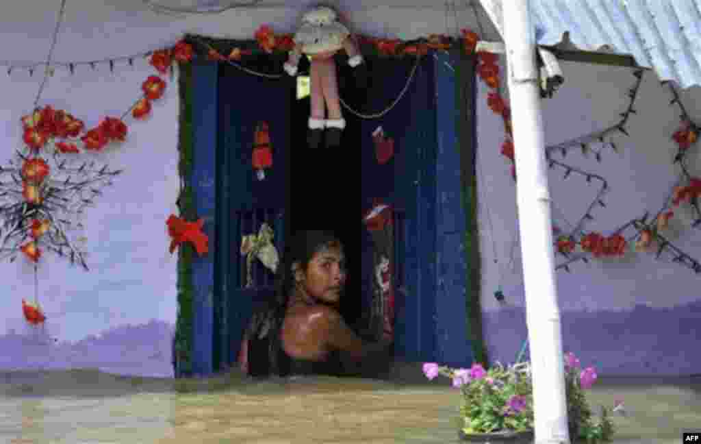 Xiomara Herrera, 13, enters her flooded home in El Porvenir, southern Colombia, Friday, Dec. 9, 2011. Torrential rains have caused devastating floods and widespread damage in the country for much of the past two years. Meteorologists blame the rains on La