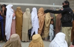 Women wait to receive cash under the government Ehsaas Emergency Cash Programme for families in need, during a government-imposed nationwide lockdown to help contain the spread of the coronavirus, in Peshawar, Pakistan, Monday, April 13, 2020