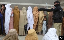 Women wait to receive cash under the government Ehsaas Emergency Cash Programme for families in need, during a government-imposed nationwide lockdown to help contain the spread of the coronavirus, in Peshawar, Pakistan, Monday, April 13, 2020
