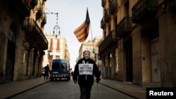 A man wearing a Guy Fawkes mask holds an Estelada, a Catalan pro-independence flag, as he walks towards a protest against a separatism-related police operation, in Barcelona, Spain, Oct. 28, 2020. His signs oreads "Enough repression. Independence."