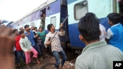 A volunteer breaks the glass of a train compartment window to rescue passengers trapped after an accident near Khatauli, in the northern Indian state of Uttar Pradesh, Aug. 19, 2017.