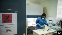 In a photo taken June 19, 2020, a specialist secures samples taken from patients at a South Sudan laboratory that tests for the coronavirus in Juba. Falling oil prices, the pandemic and floods pushed South Sudan to seek a loan from the IMF.