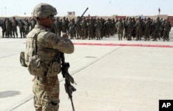 FILE - U.S. military personal stands guard during a graduation ceremony for Afghan troops, in Lashkargah, capital of southern Helmand province, Afghanistan.