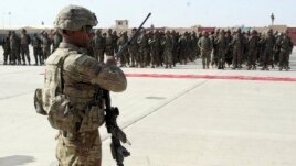 U.S. military personal stands guard during a graduation ceremony for Afghan troops, in Lashkargah, capital of southern Helmand province, Afghanistan.