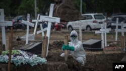 지난 15일 인도네시아 동부 자바 수라바야의 묘지에서 장례식 직원이 신종 코로나바이러스 감염증(COVID-19) 사망자 시신이 안장된 장소에 나무비석을 꽂고 있다.
