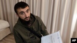 FILE - Chechen blogger Tumso Abdurakhmanov holds a letter from Interpol during an interview with The Associated Press somewhere in Poland, Nov. 14, 2018.