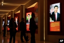 Visitors walk past images of China's past and present leaders, from left, Mao Zedong, Deng Xiaoping, Jiang Zemin, Hu Jintao and Xi Jinping on display at an exhibition on the Long March at the military museum in Beijing, Oct. 24, 2016.