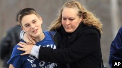 A ninth grader at Chardon High School, is hugged by his mother following a shooting at his school, Feb 27, 2012.