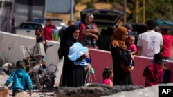 Orang-orang membopong anak-anak mereka untuk menyeberang ke Suriah dengan berjalan kaki dari timur Lembah Bekaa, Lebanon, Sabtu, 5 Oktober 2024. (Foto: Hassan Ammar/AP Photo)