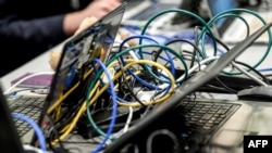 FILE - Wires are plugged into laptop computers as people work during the 11th International Cybersecurity Forum, January 22, 2019.