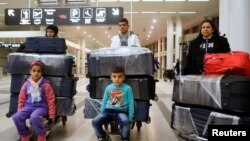 FILE - The al-Qassab family, Iraqi Christian refugees from Mosul, walk through the Beirut international airport ahead of their travel to the United States, in Beirut, Lebanon, Feb. 8, 2017.