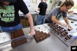 In this Sept. 26, 2014, file photo, smaller-dose pot-infused brownies are divided and packaged at The Growing Kitchen in Boulder, Colo. Edible marijuana products in Colorado may soon come labeled with a red stop sign as the state is finalizing work on new rules for the appearance of edible marijuana. A draft of those rules released Tuesday, Aug. 11, 2015