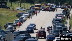 La gente camina junto a autos estacionados a los costados de una carretera, cerca de la escena del tiroteo en Apalachee High School en Winder, Georgia, EEUU, 4 de septiembre de 2024.