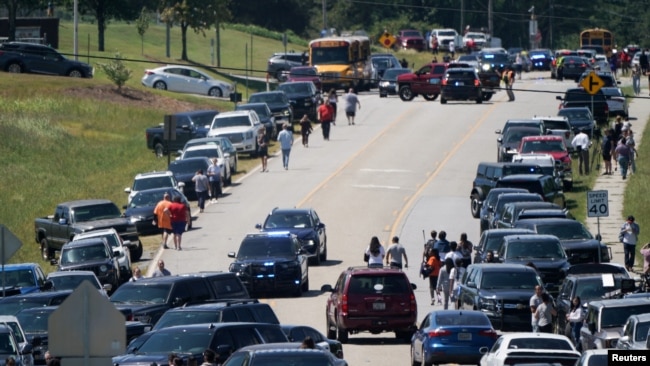 La gente camina junto a autos estacionados a los costados de una carretera, cerca de la escena del tiroteo en Apalachee High School en Winder, Georgia, EEUU, 4 de septiembre de 2024.