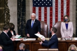 FILE - Then-Vice President Pence hands the West Virginia certification to staff as Speaker of the House Nancy Pelosi (D-CA) listens during a joint session of Congress after working through the night, at the Capitol in Washington, Jan. 7, 2021.