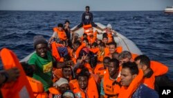 Migrants aboard a rubber dinghy off the Libyan coast are provided of life vests by rescuers aboard the Open Arms aid boat, of the Proactiva Open Arms NGO, June 30, 2018. The migrants were rescued as Italy's right-wing Interior Minister Matteo Salv
