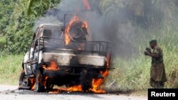 A Congolese soldier from the Armed Forces of the Democratic Republic of Congo stands next to their burning vehicle after an ambush near the village of Mazizi in North Kivu province, Jan. 2, 2014.