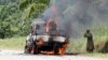 A Congolese soldier from the Armed Forces of the Democratic Republic of Congo stands next to their burning vehicle after an ambush near the village of Mazizi in North Kivu province, Jan. 2, 2014.