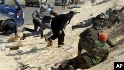 Libyan rebel fighters take cover during a shelling along Benghazi -Ajdabiyah road near Ajdabiyah March 24, 2011.