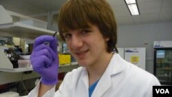 Jack Andraka, 16, with his pancreatic cancer sensor strip at the Johns Hopkins lab in Baltimore. (VOA/J. Taboh) 
