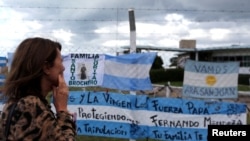 Seorang perempuan memperhatikan berbagai spanduk di pagar pangkalan Angkatan Laut Argentina, yang bertuliskan dukungan untuk 44 awak kapal selam ARA San Juan yang hilang di tengah laut saat berlayar kembali ke Mar del Plata, Argentina, 20 November 2017